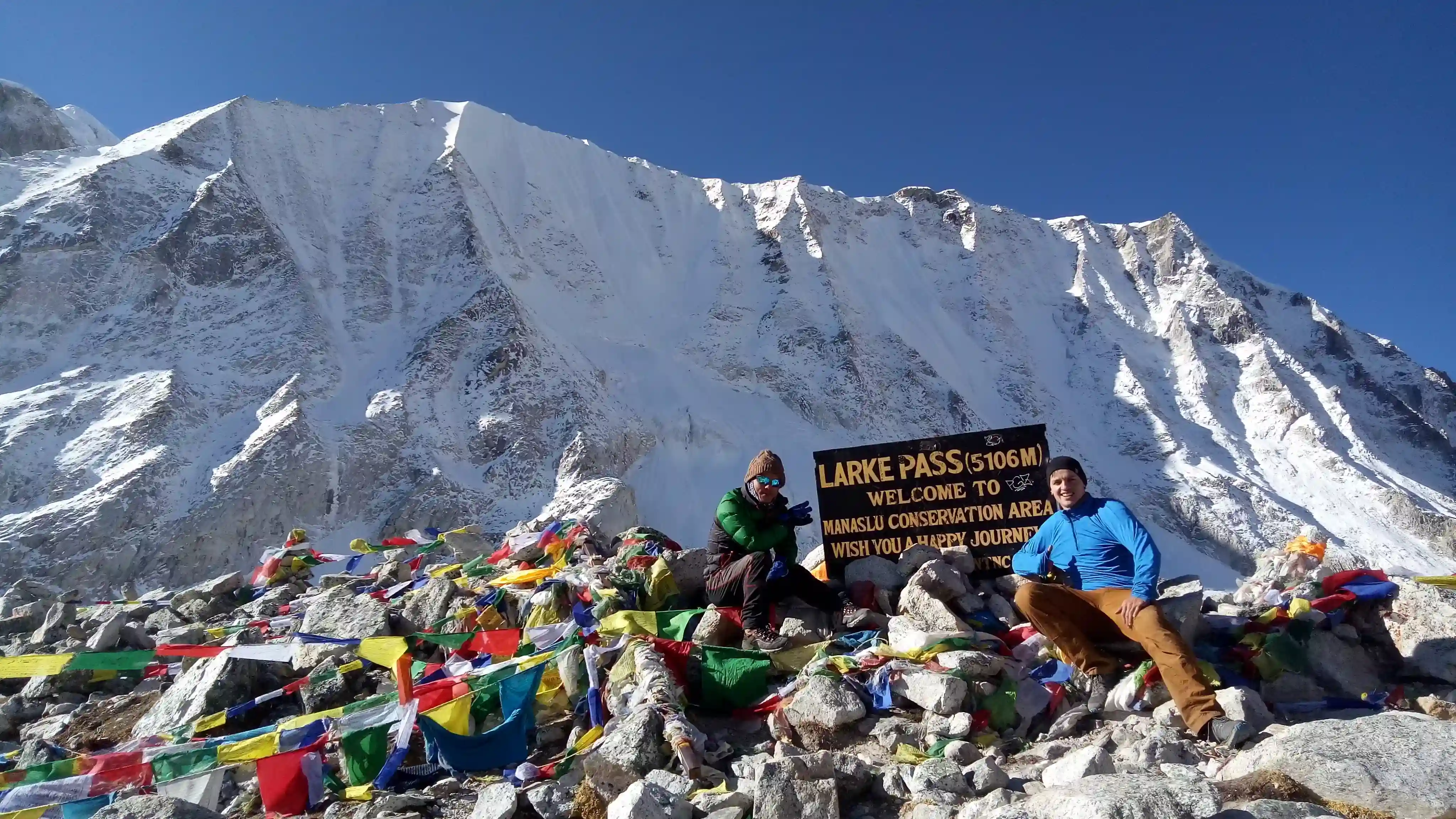 Trekkers Standing Among Prayer Flags with Snowy Himalayan Mountains
