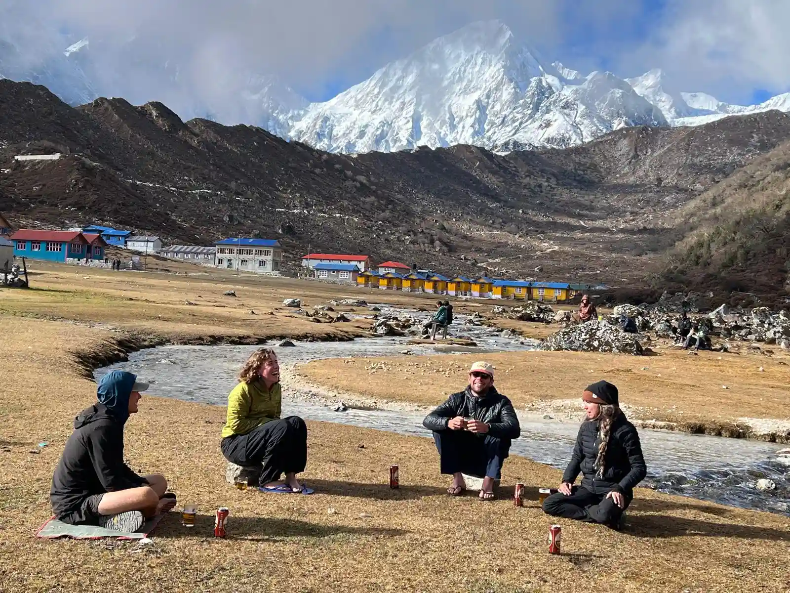 Trekkers resting in a Himalayan village with snow-covered mountains in the background